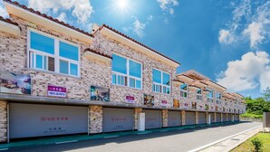 A row of brick buildings with multiple garage doors, each marked with a number. - Yeosu King Pension Tel (Yeosu)