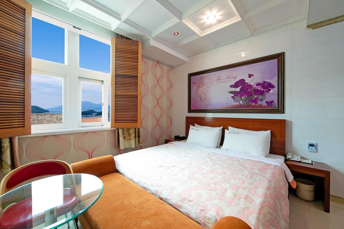 A hotel room with a bed, a glass table, and a chair.
