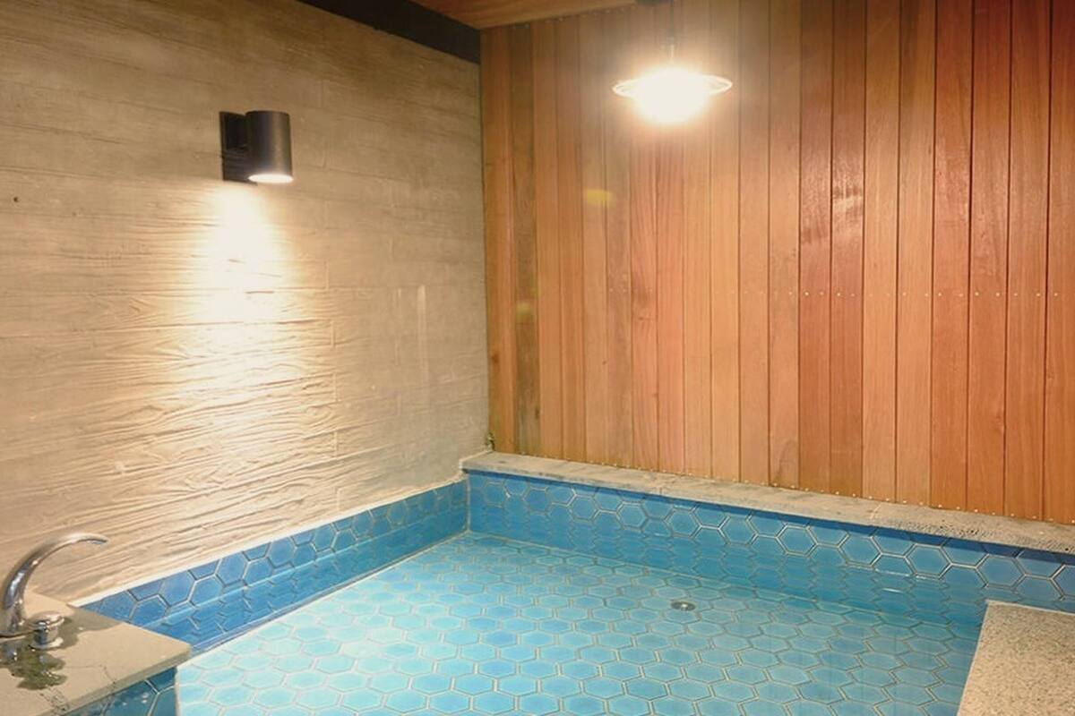 Eine kleine, private Sauna mit sechseckischen Fliesen, einer Holzwand und einer einzelnen Leuchte.