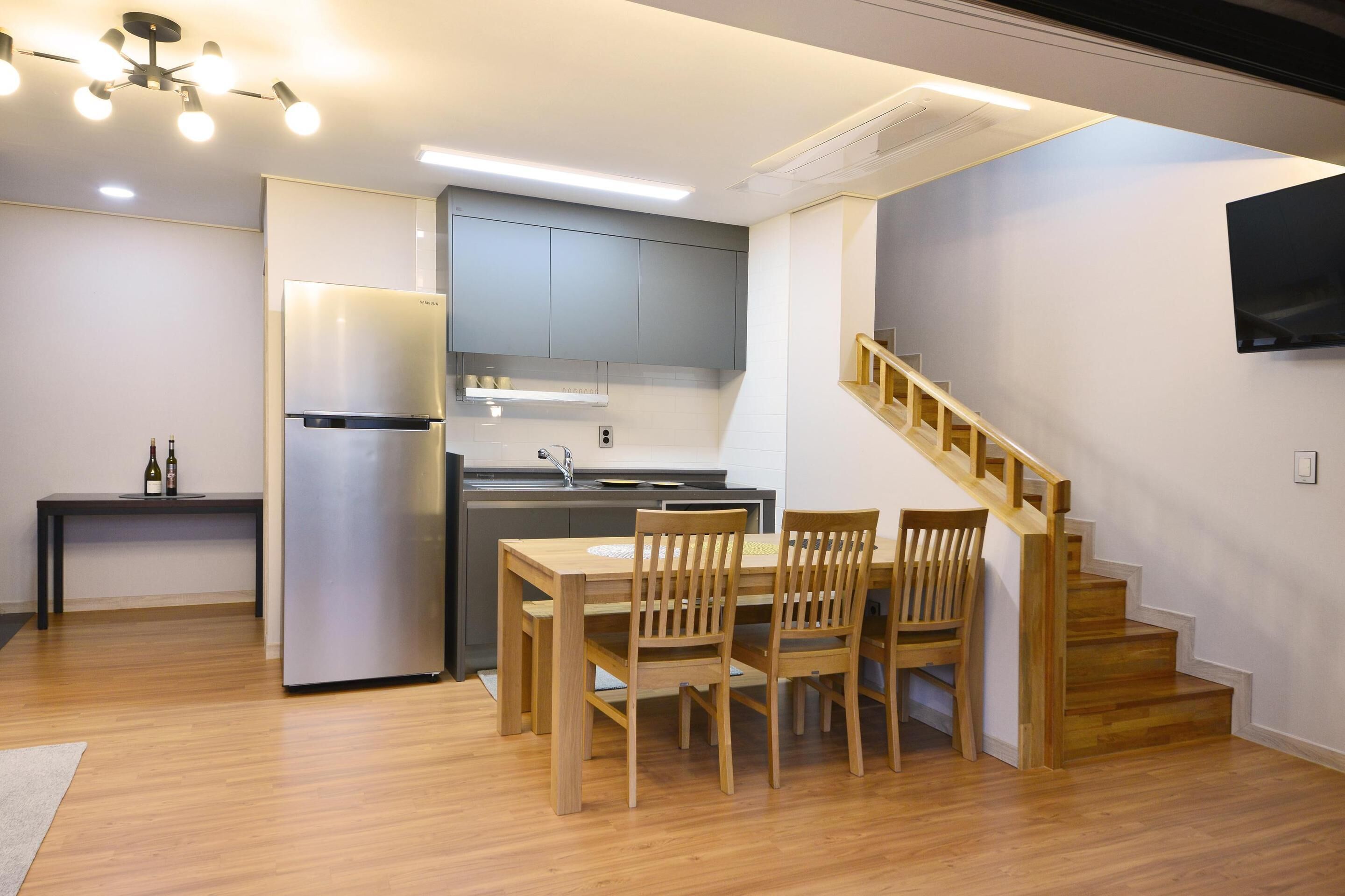 A modern kitchen with a built-in refrigerator, wooden dining table, and chairs.