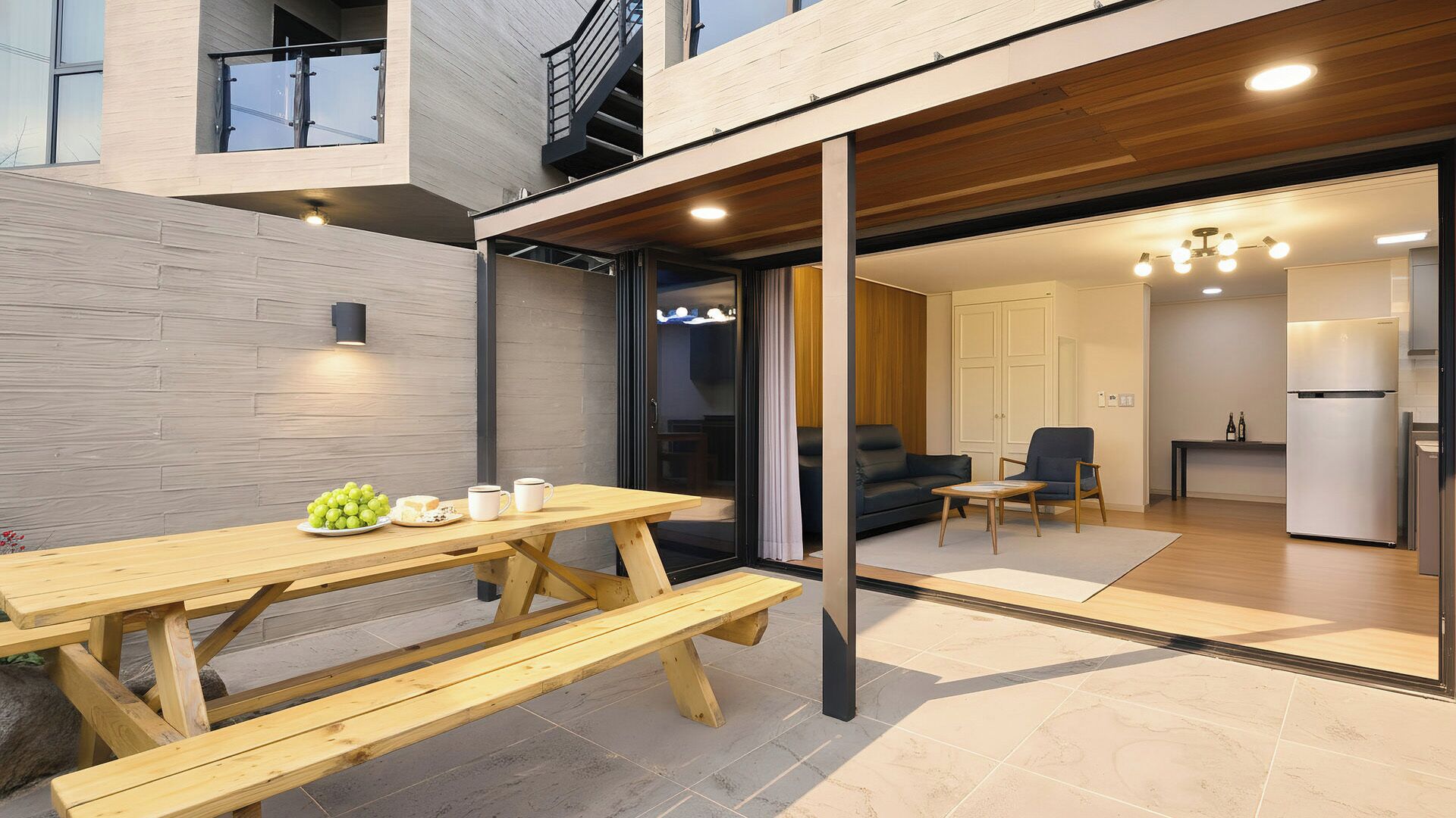 A modern apartment with a wooden dining table, a sofa, and a kitchen area.