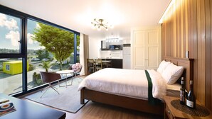 Une chambre d’hôtel moderne avec une grande fenêtre, un lit, un bureau et une chaise.