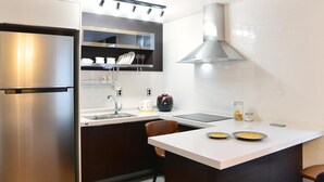 Une cuisine moderne équipée d’un réfrigérateur en acier inoxydable, d’un four encastré, d’un évier et d’un plan de travail sur lequel se trouvent une bouilloire et un bocal de citrons.