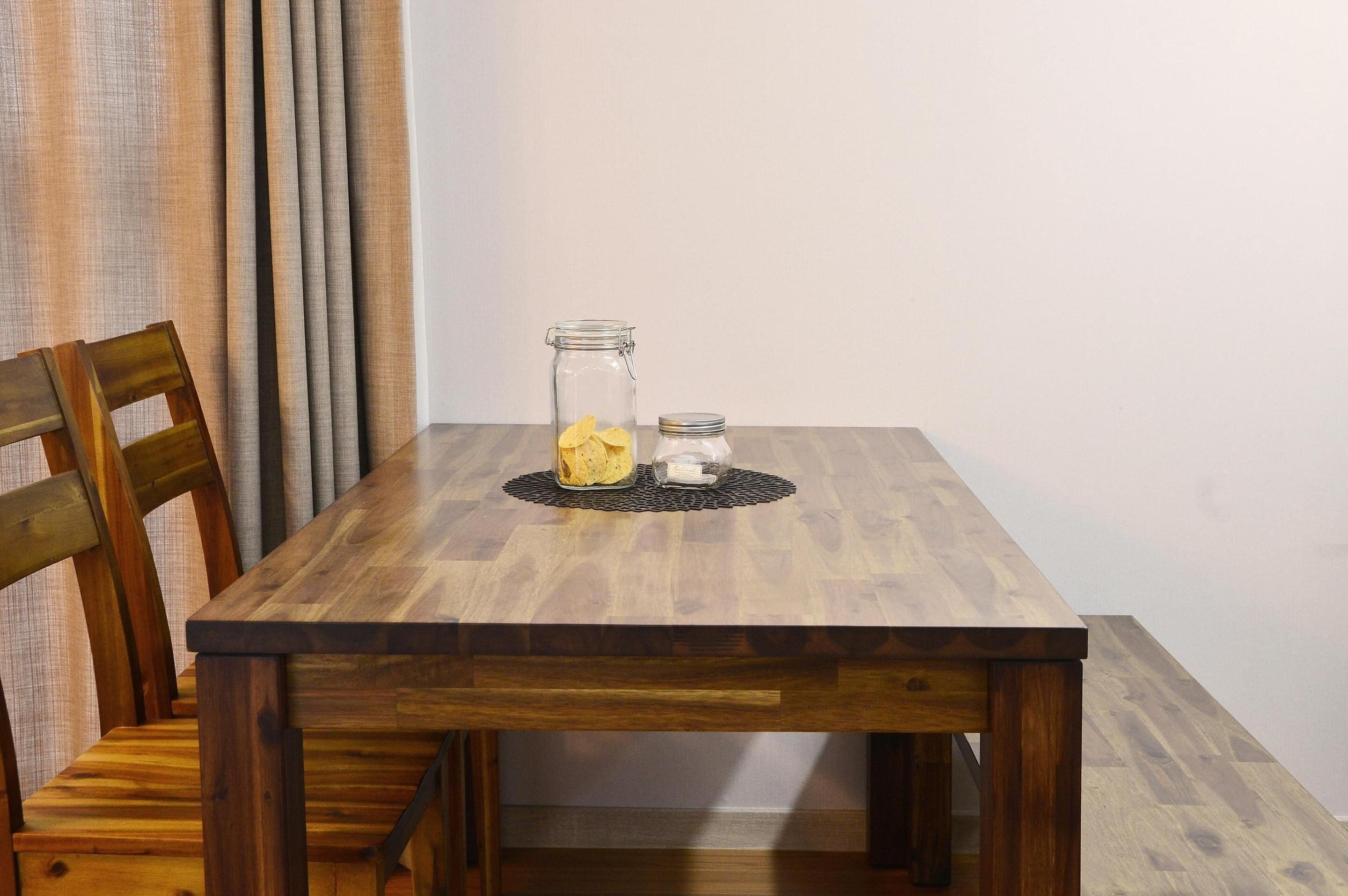 A wooden table with two glass jars and a woven placemat.