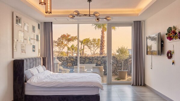 Une chambre à coucher avec un lit, une grande fenêtre et une vue sur l’extérieur.