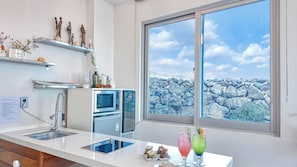 A modern kitchen with a large window, built-in oven, and a countertop with a tablet and decorative items.