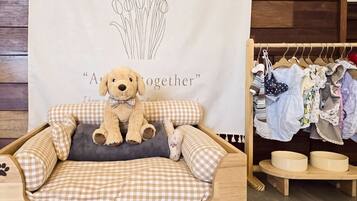 A cozy room with a plush dog bed, a wall with a floral design, and a clothing rack with various garments.