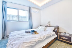 A neatly made bed with white linens, a bedside table with a lamp, and a window with curtains. - Seogwipo Dawa Pool Villa Pension (Seogwipo)