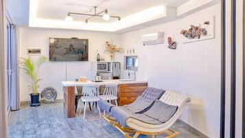 Un espace de vie moderne comprenant une cuisine, un coin repas et un coin salon confortable avec un fauteuil à bascule.