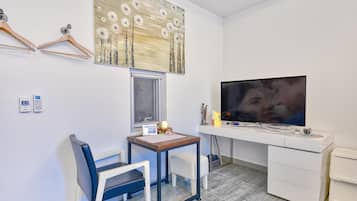 Ein modernes Zimmer mit Schreibtisch, Stuhl, Fernseher und einem dekorativen Gemälde.