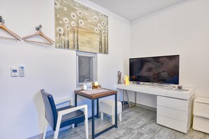 Una habitación moderna con escritorio, silla, televisor y un cuadro decorativo.