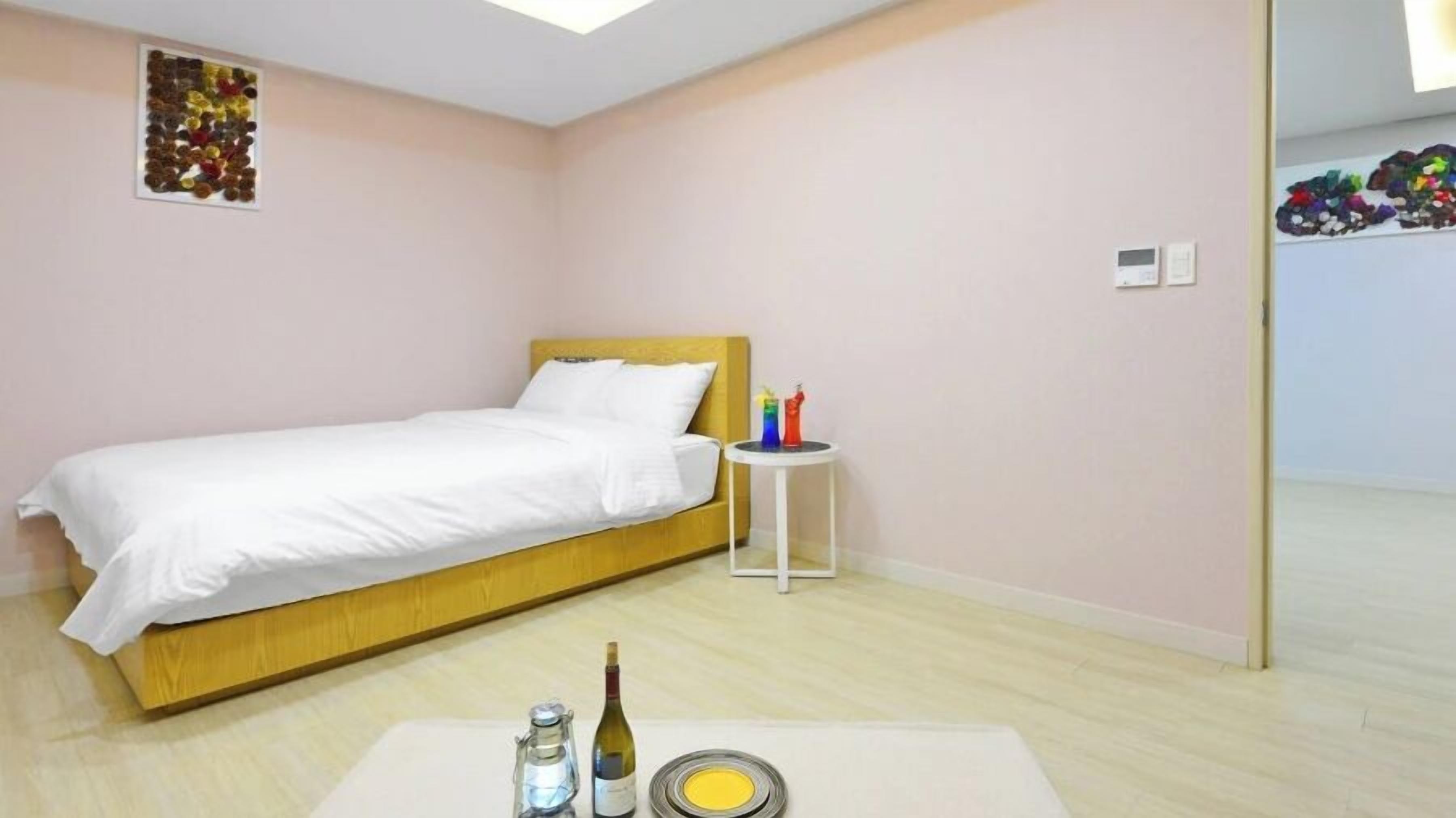 Ein Schlafzimmer mit einem Bett, einem Nachttisch und einer Weinflasche.