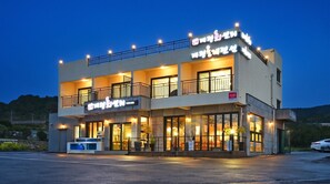 A multi-story building with a balcony and illuminated signage, likely a hotel or commercial establishment. - Seogwipo Daepyeong Olleh Pension (Seogwipo)