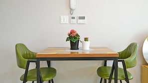 A dining table with two green chairs, a potted plant, and a wall-mounted phone. - Seogwipo Daepyeong Olleh Pension (Seogwipo)