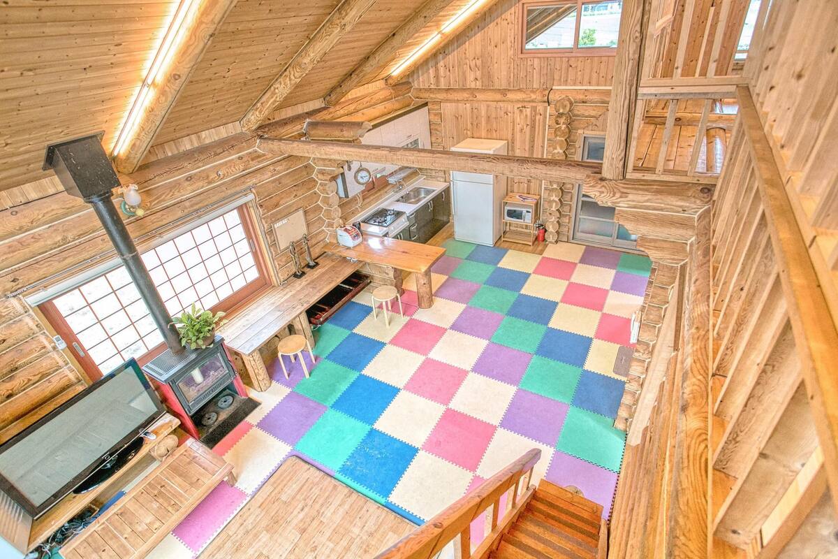 A cozy wooden cabin with a kitchen, a dining area with a colorful checkered floor, and a television.