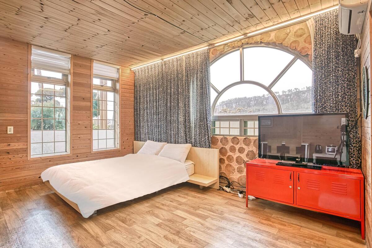 A bedroom with a bed, a TV, and a red cabinet.
