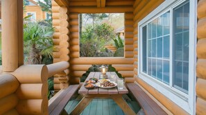 Une cabane en rondins de bois, avec une table à manger dressée pour deux personnes, agrémentée d’une lanterne et de différents plats.