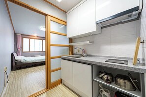 Een kleine keuken met een spoelbak, kastjes en een aanrecht.