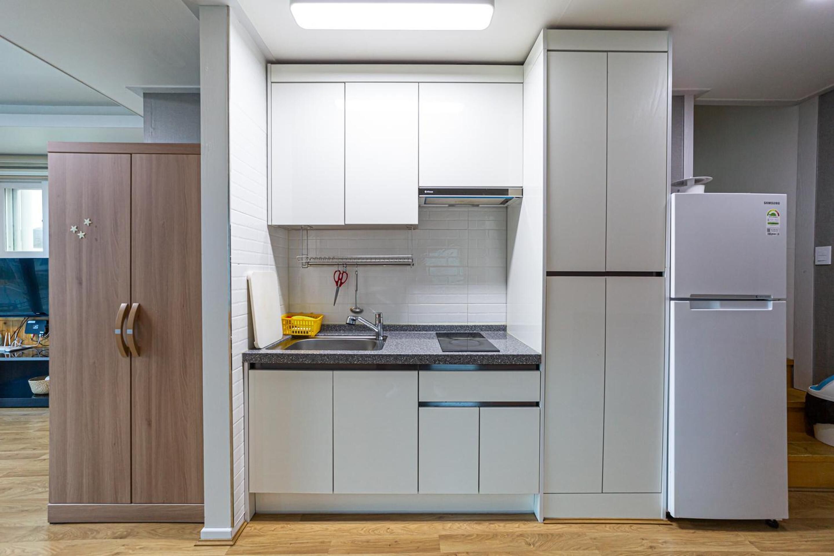 A modern kitchen with white cabinets, a stainless steel sink, and a white refrigerator.