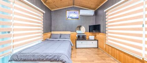 A bedroom with a bed, bedside table, and a wall-mounted TV.