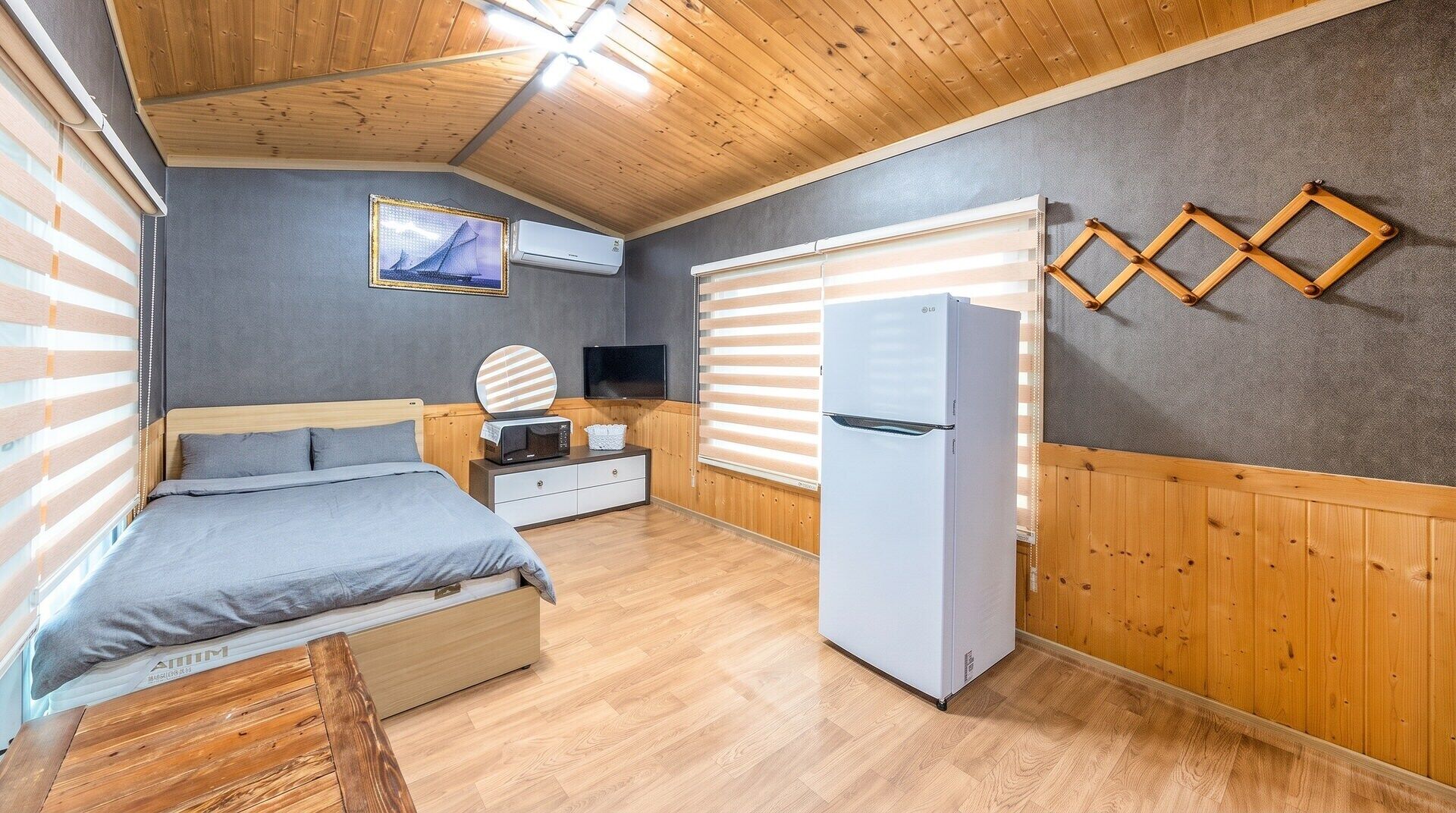 Ein Schlafzimmer mit einem Bett, einem Fernseher, einer Mikrowelle und einem Kühlschrank.