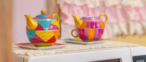 Two colorful teapots on a microwave.
