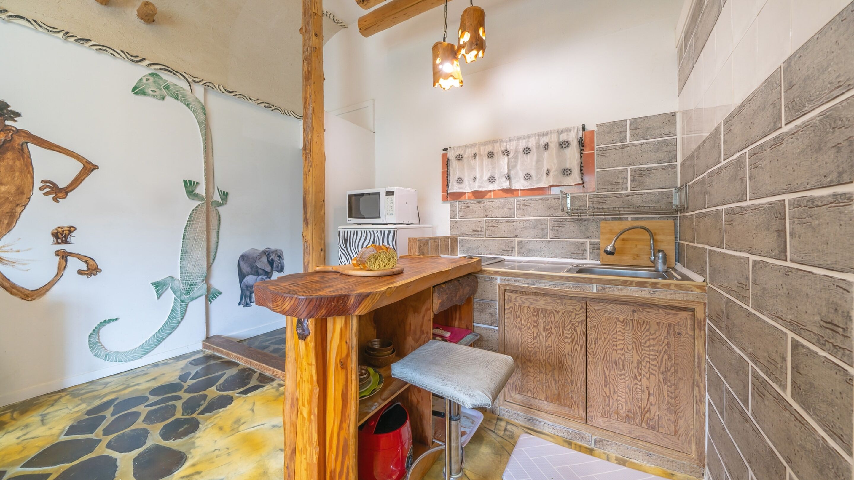 A compact kitchen with a wooden countertop, a microwave, a sink, and a zebra-patterned backsplash.