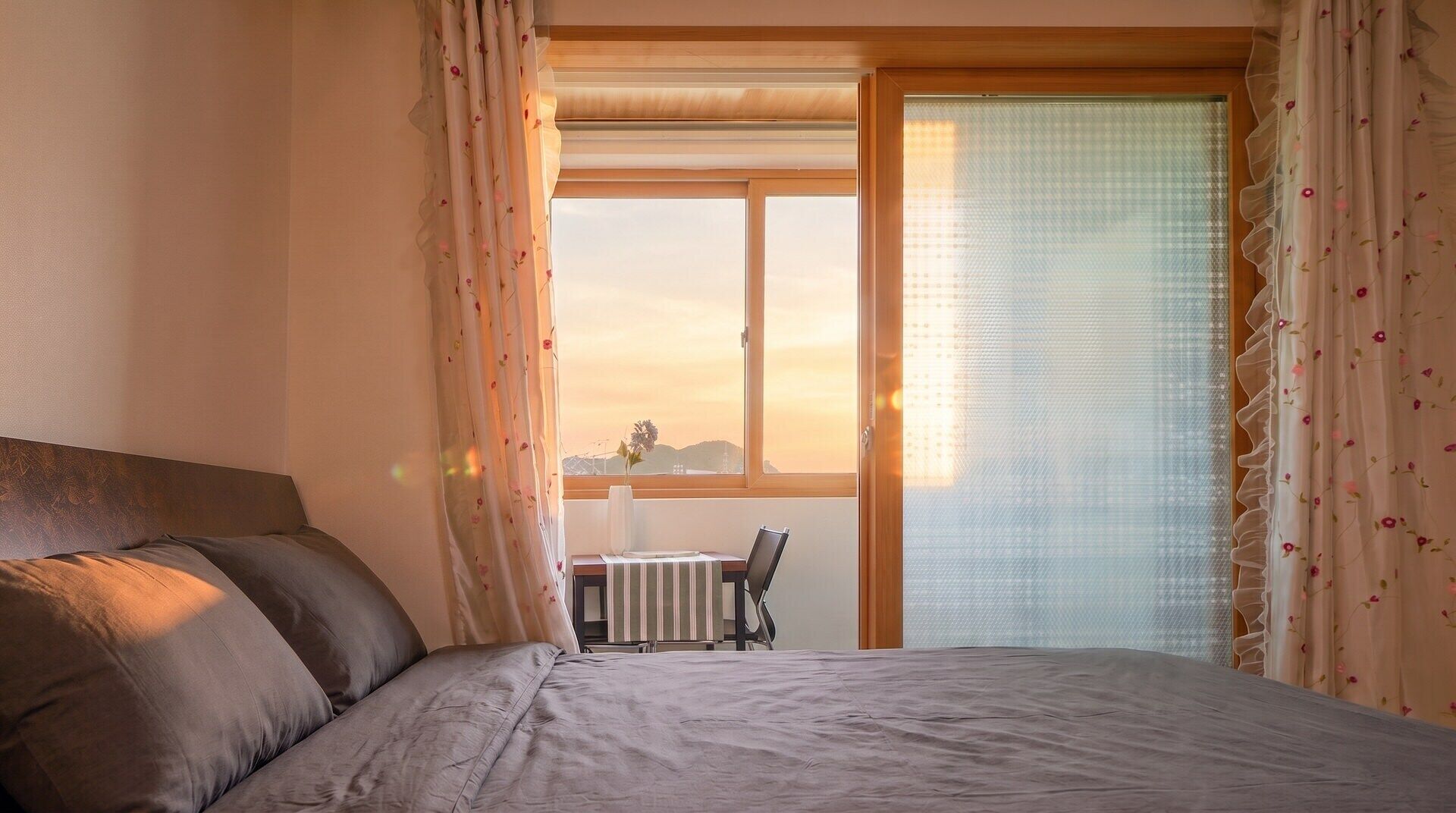 Un dormitorio con cama, ventana y vistas al exterior.