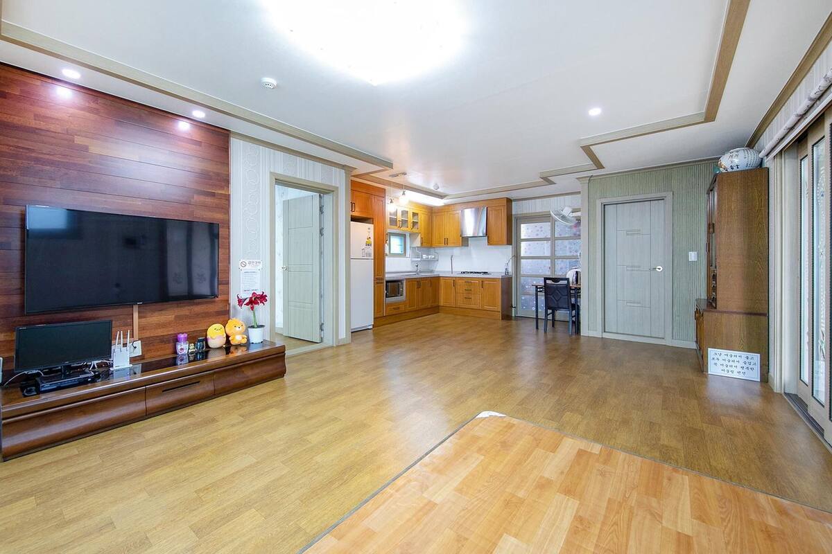 Amplia sala de estar con televisión de pantalla plana, piso de madera y mueble empotrado para entretenimiento.