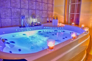 A hot tub with LED lights, candles, and a glass on the side. - Yangpyeong Yoon & Park Spa Pension (Yangpyeong)
