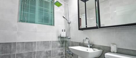 A bathroom with a shower, sink, toilet, and a window with blinds.