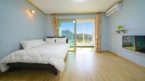 Un dormitorio con cama, televisor y vistas al exterior.