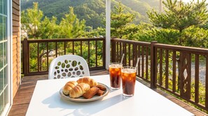 Ein Balkon mit Tisch für zwei Personen, dekoriert mit einem Teller Croissants und Gläsern mit Eistee.