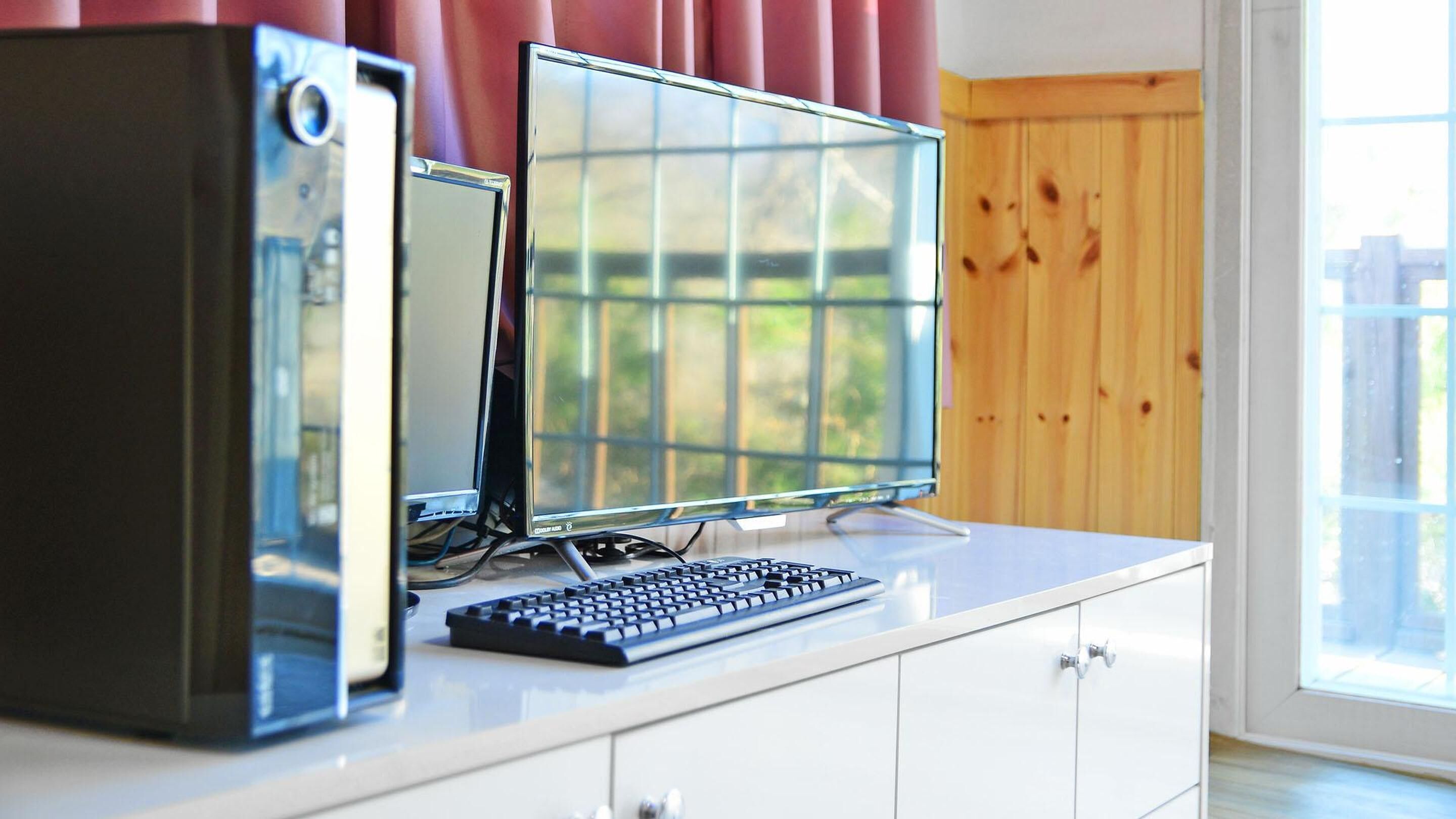 A computer setup with a desktop tower, monitor, and keyboard on a white desk.