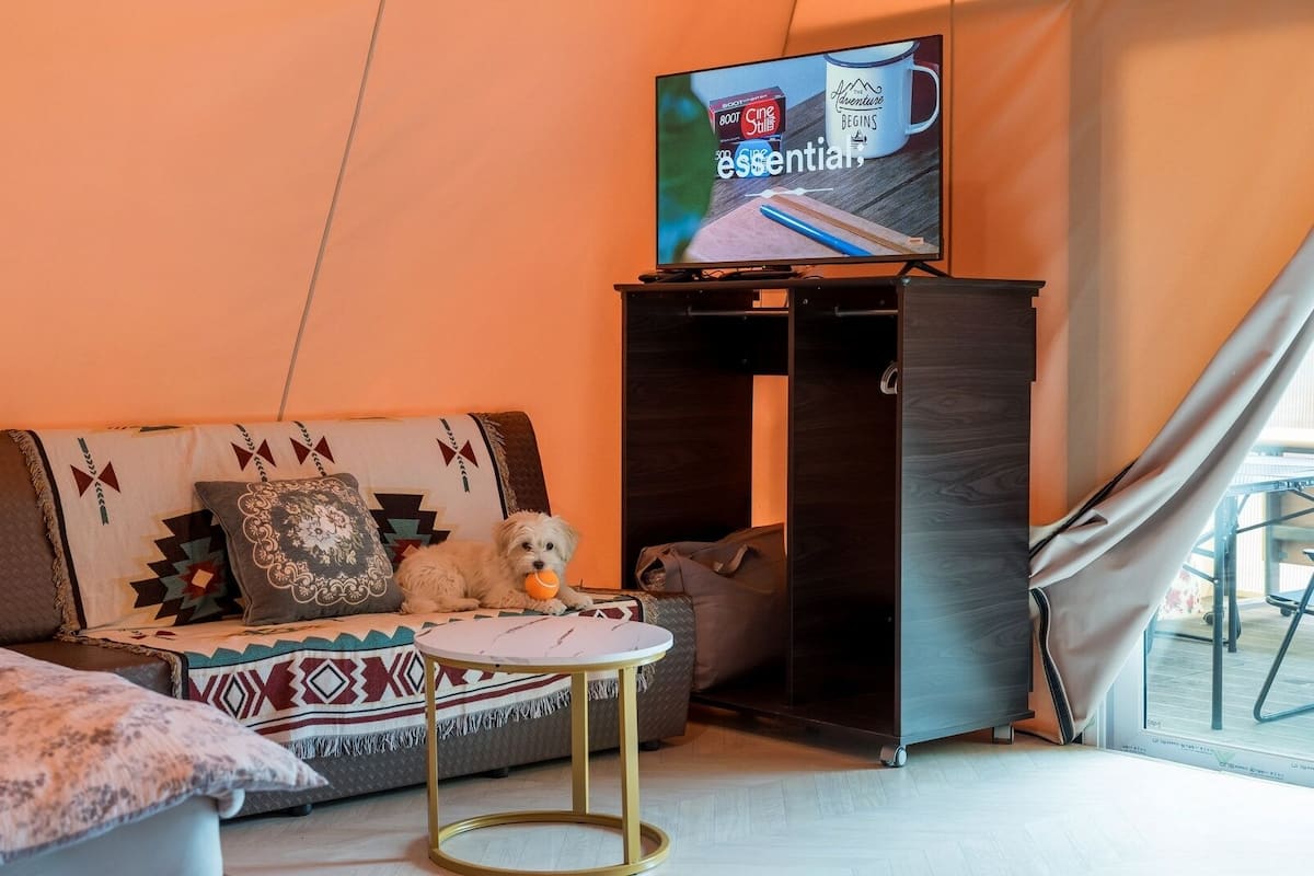 Ett mysigt vardagsrum med en soffa, ett litet runt bord, en tv och en garderob.