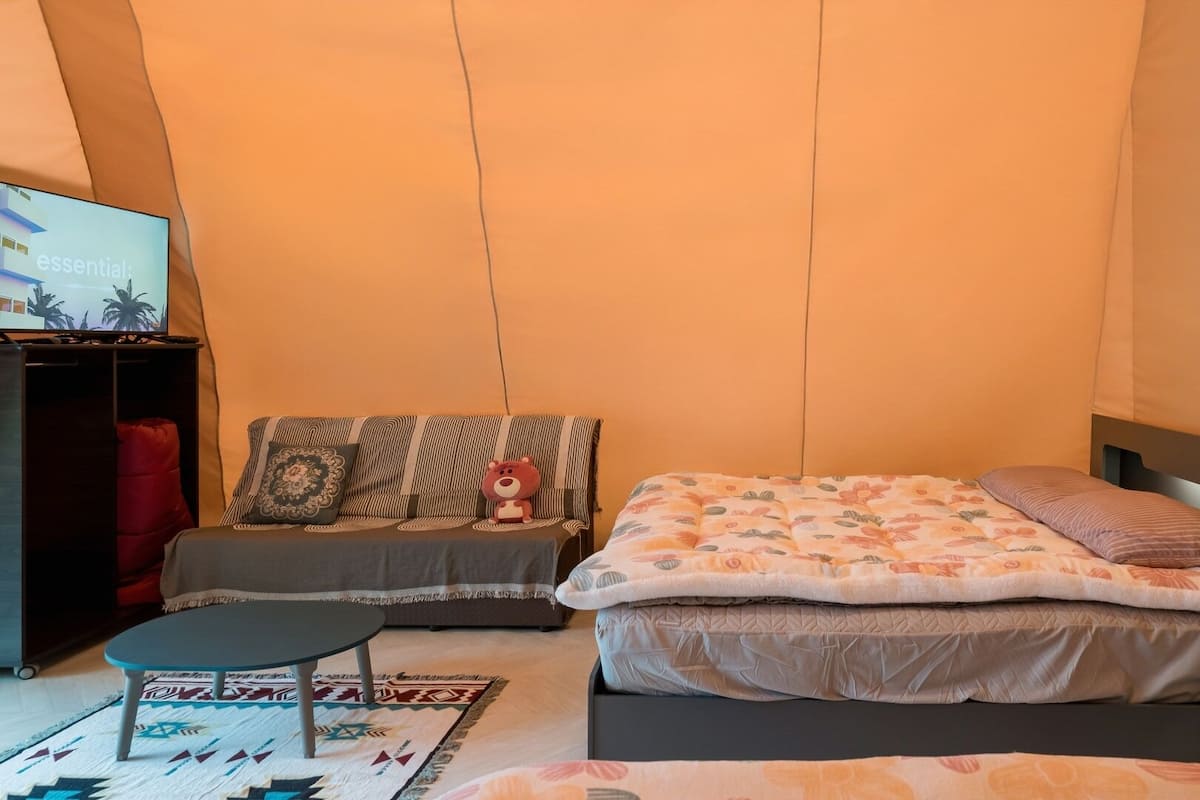 Ett sovrum med en säng, en soffa, en tv och ett litet bord.