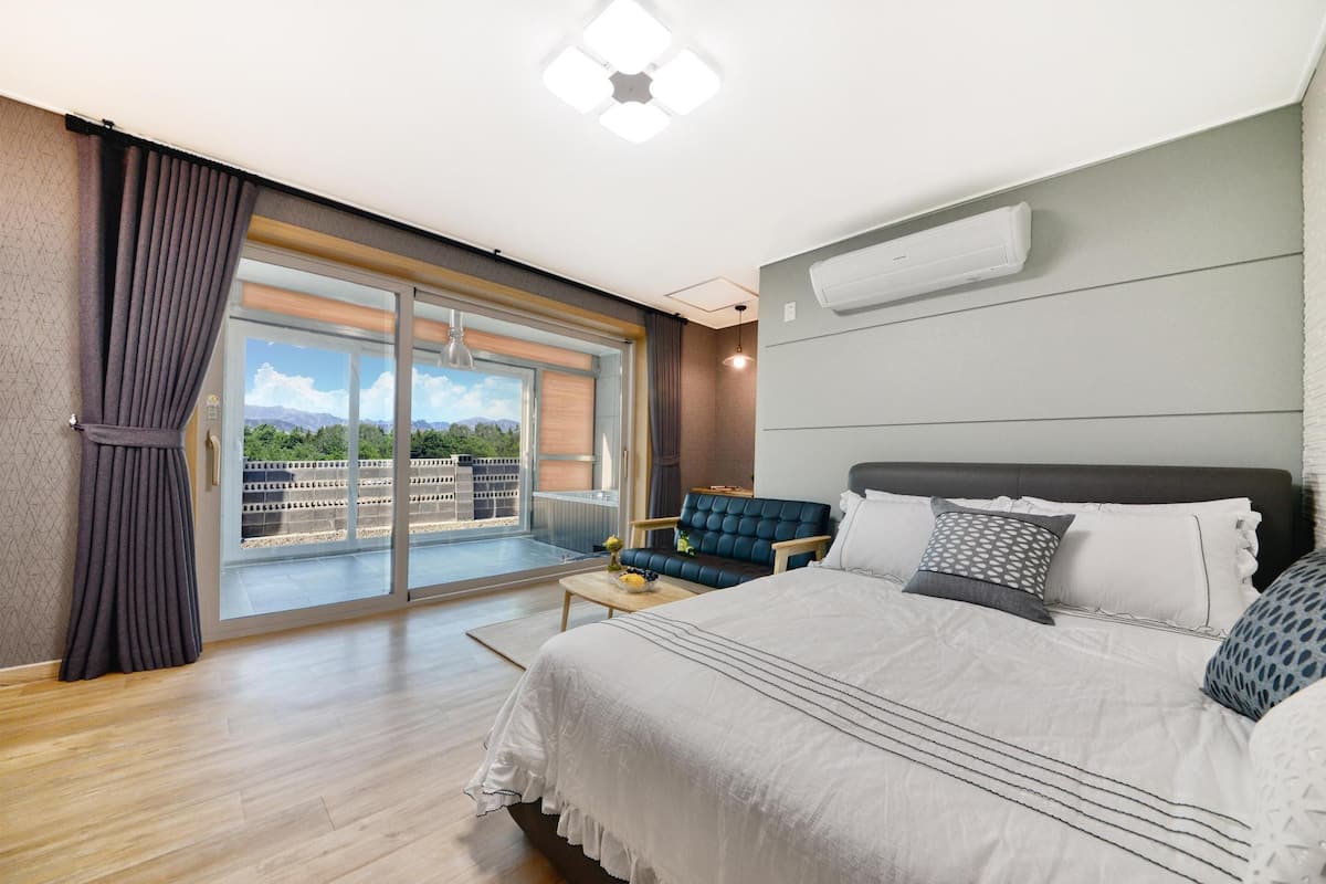 A modern bedroom with a large bed, a sofa, and a view of a balcony.