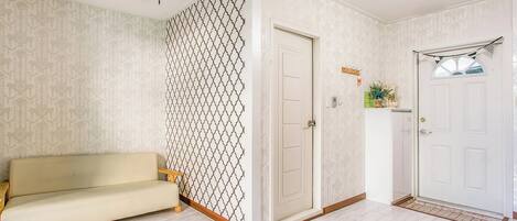 A room with a patterned wall, a sofa, a door, and a chandelier.