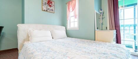 A bedroom with a bed, a window with curtains, a bedside table, and a wall-mounted air purifier.
