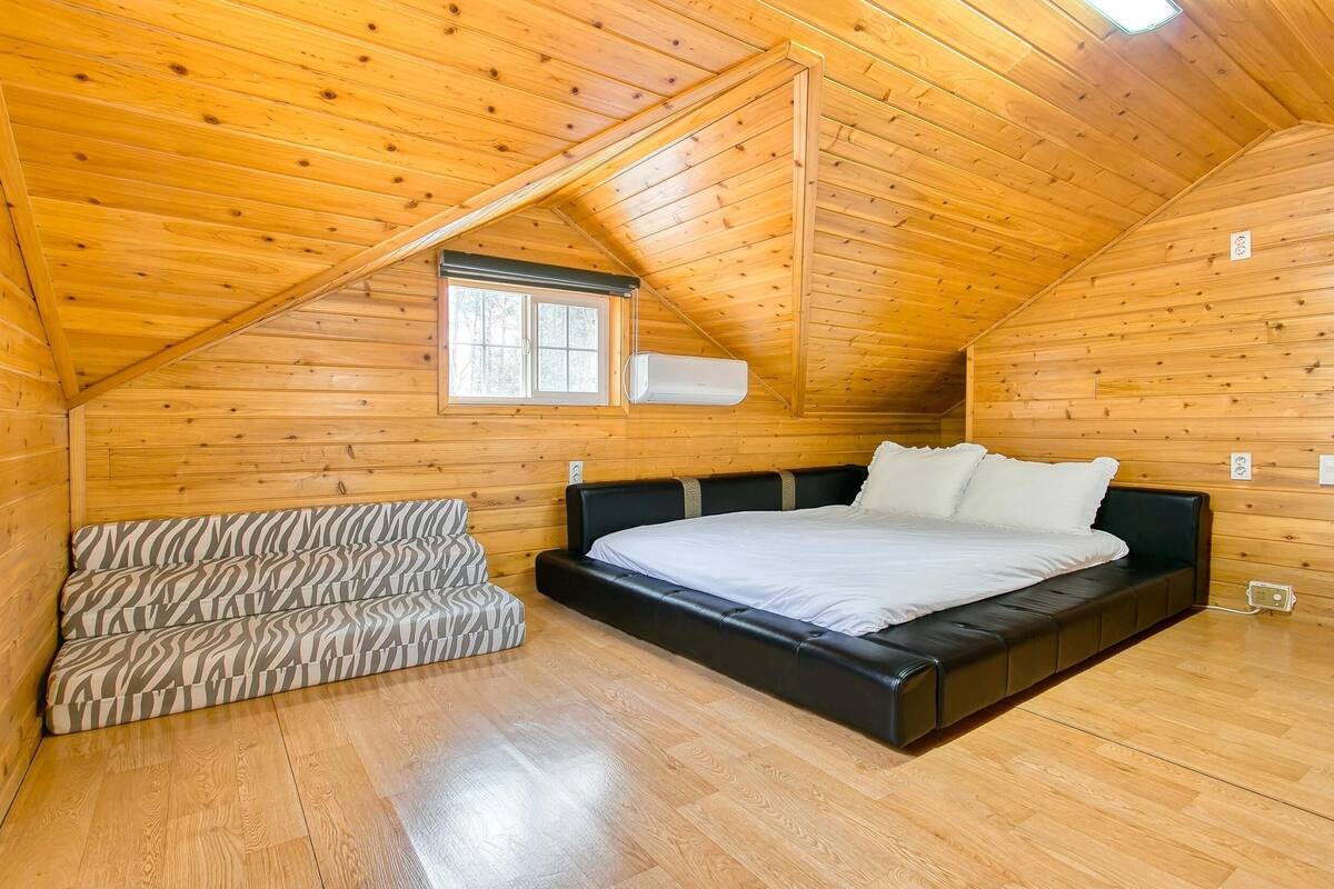 A wooden-paneled room with a bed, a window, and a built-in bench.