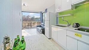 A modern kitchen with a green backsplash, a built-in oven, and a large window overlooking a patio area. - Gyeongju Hyu Plus Pension (Gyeongju)