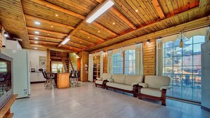A spacious living area with wooden ceiling beams, a sofa, a dining table, and a kitchen area. - Gyeongju Hyu Plus Pension (Gyeongju)