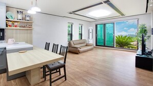 Un salon moderne avec un coin repas, de grandes fenêtres et une vue sur la verdure.