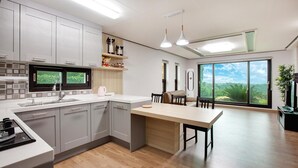 Une cuisine moderne avec des meubles gris, un plan de travail en bois et une grande fenêtre donnant sur un paysage verdoyant.