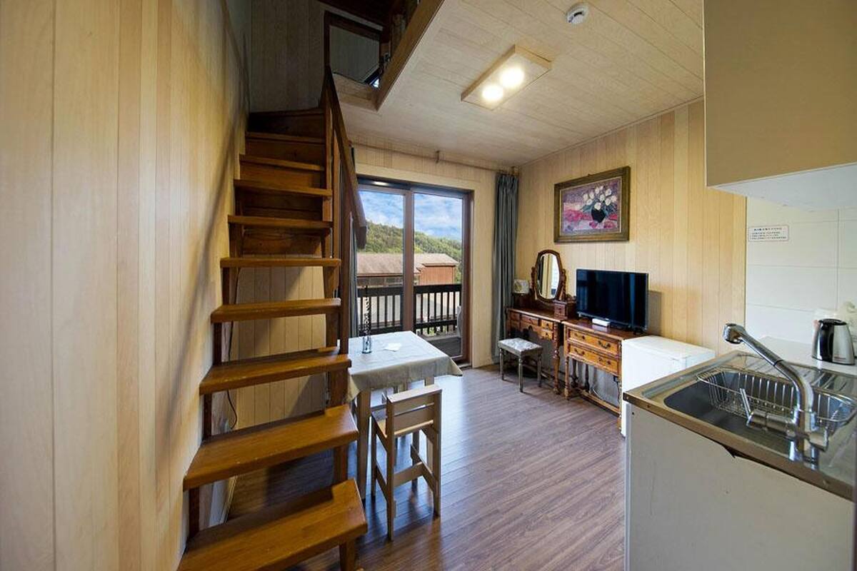 Une cuisine chaleureuse avec un plancher en bois, une table à manger, un téléviseur et un évier.