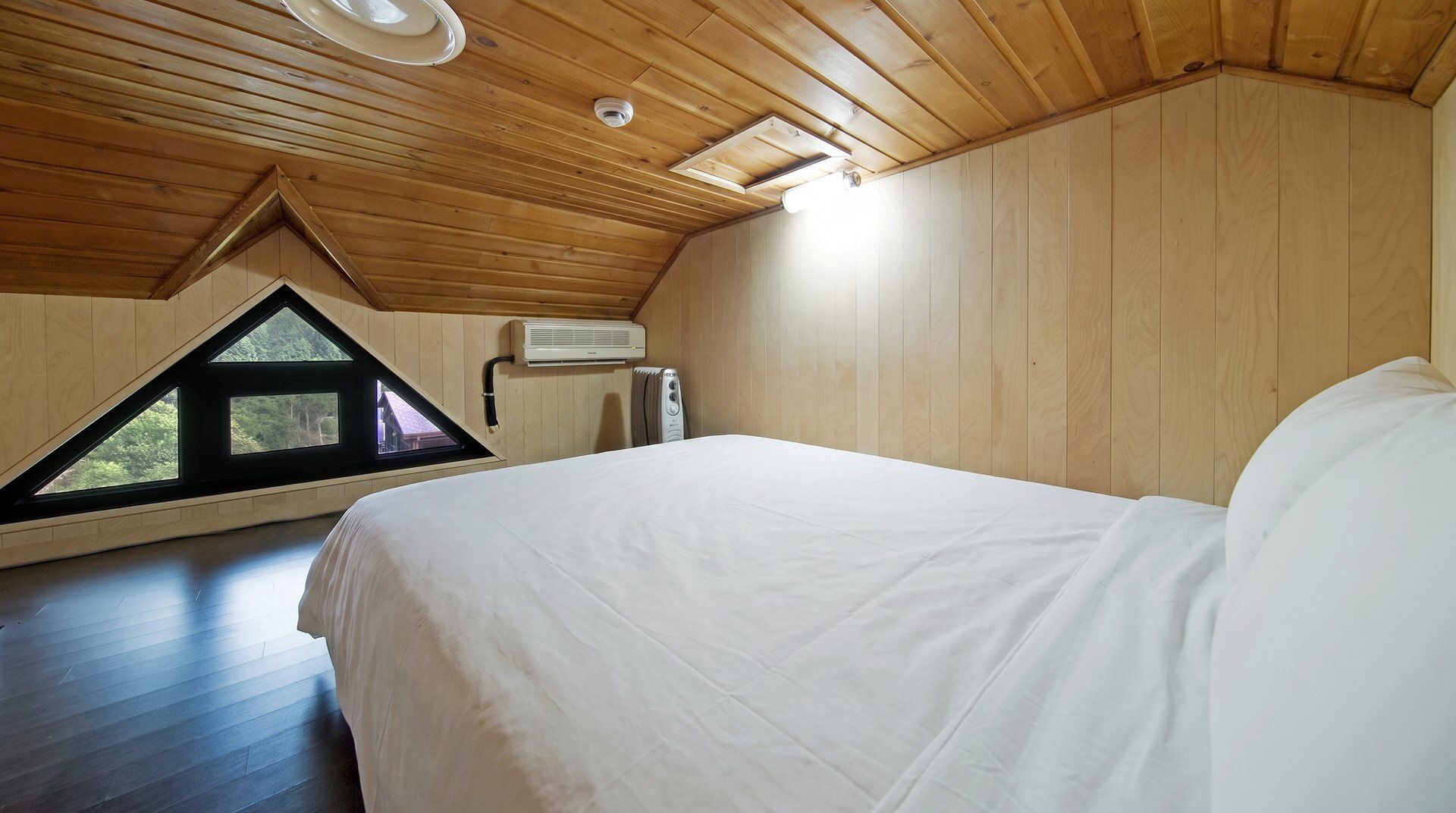 Un dormitorio con una cama grande, techo de madera y un tragaluz.