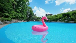 Een zwembad met een roze flamingo drijver.