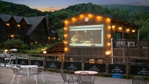 Een openlokaal gelegenheidscentrum met een podium voor optredens, omringd door houten constructies en tafels voor diners.