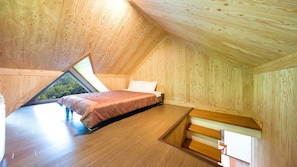Un dormitorio con techo inclinado, una cama y un tragaluz.