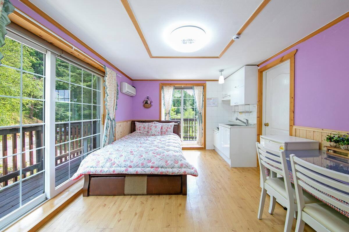 Une chambre avec un lit, un bureau et une fenêtre donnant sur un paysage verdoyant.